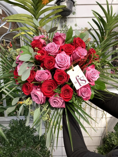 Ruby - 24 red and lilac roses with a mix of foliage. Hand-tied will be gift wrapped and in a hand-tied box.